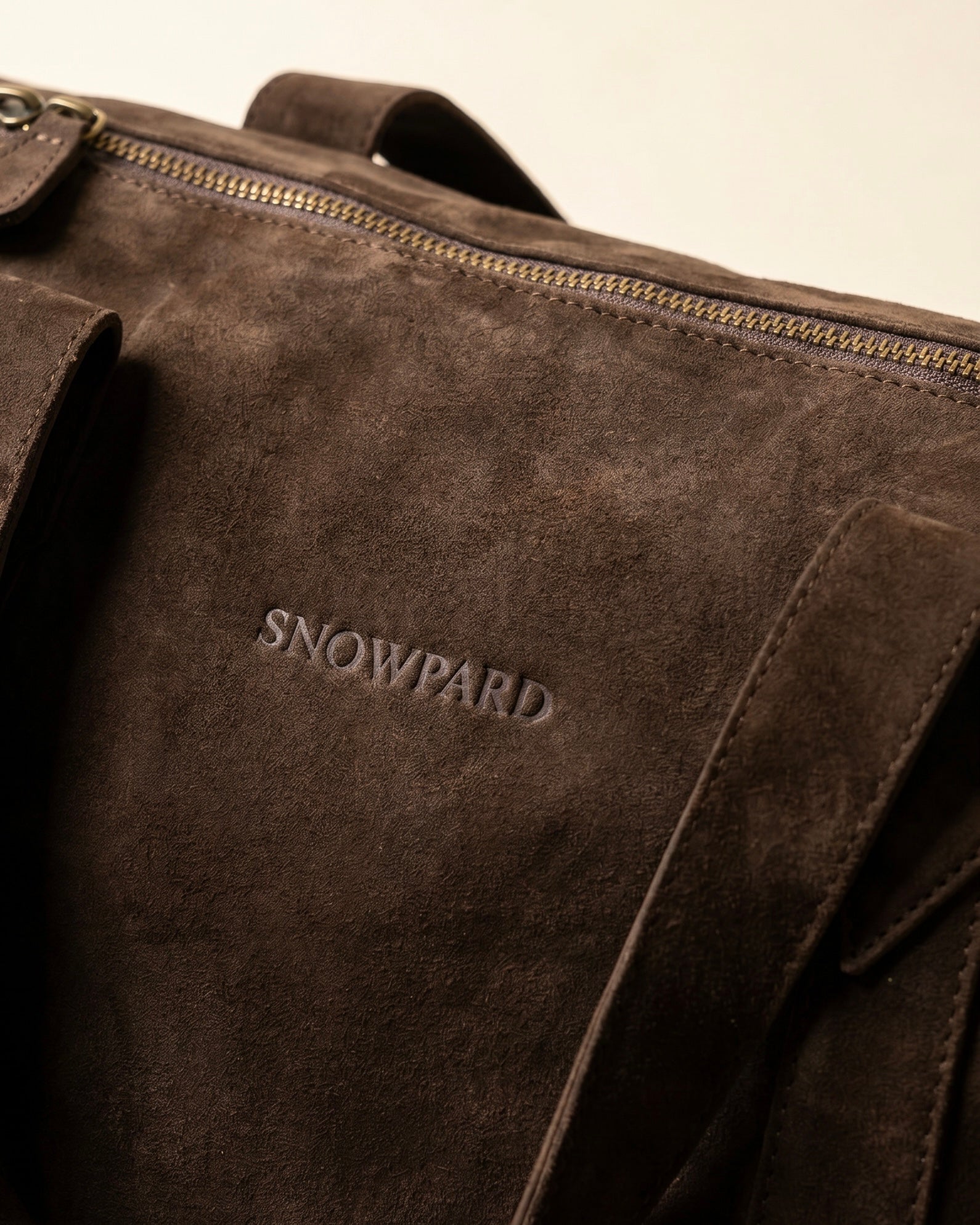 Suru Duffel chocolate brown suede duffel bag hanging by shoulder strap