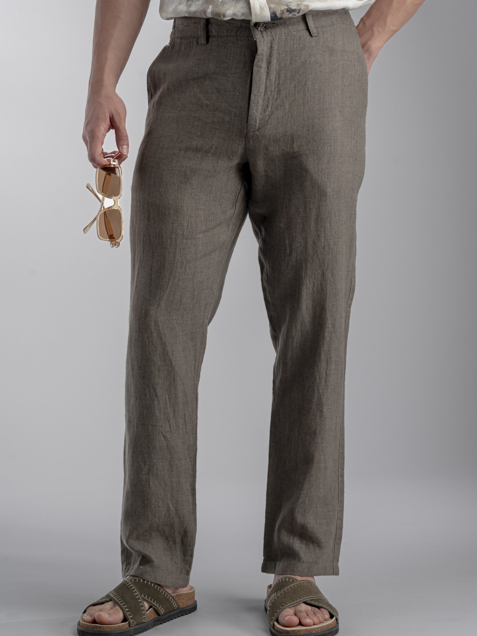 Person wearing brown Linen pants holding sunglasses