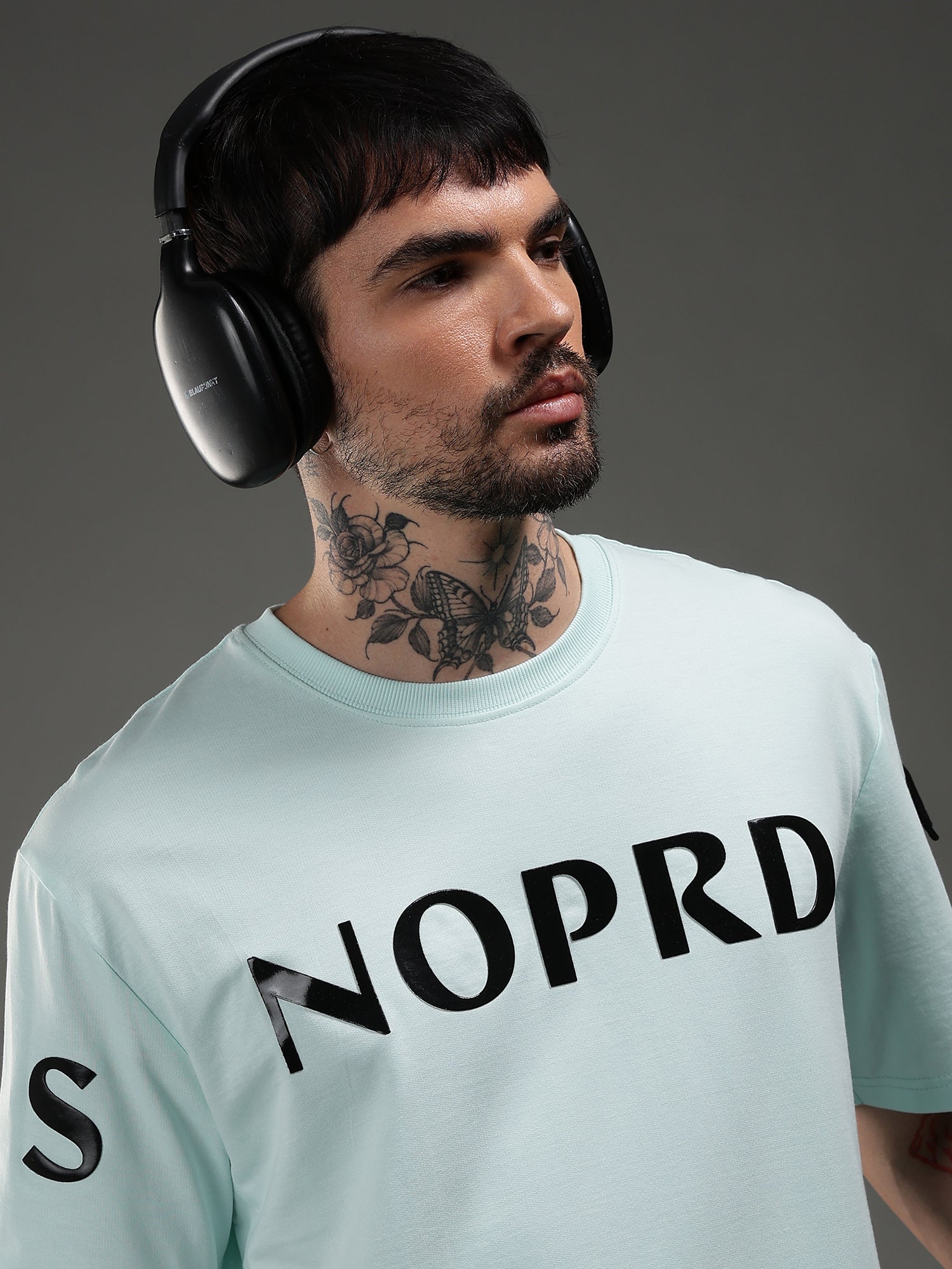 Man wearing headphones and a light blue t-shirt with 'NOPRD' printed