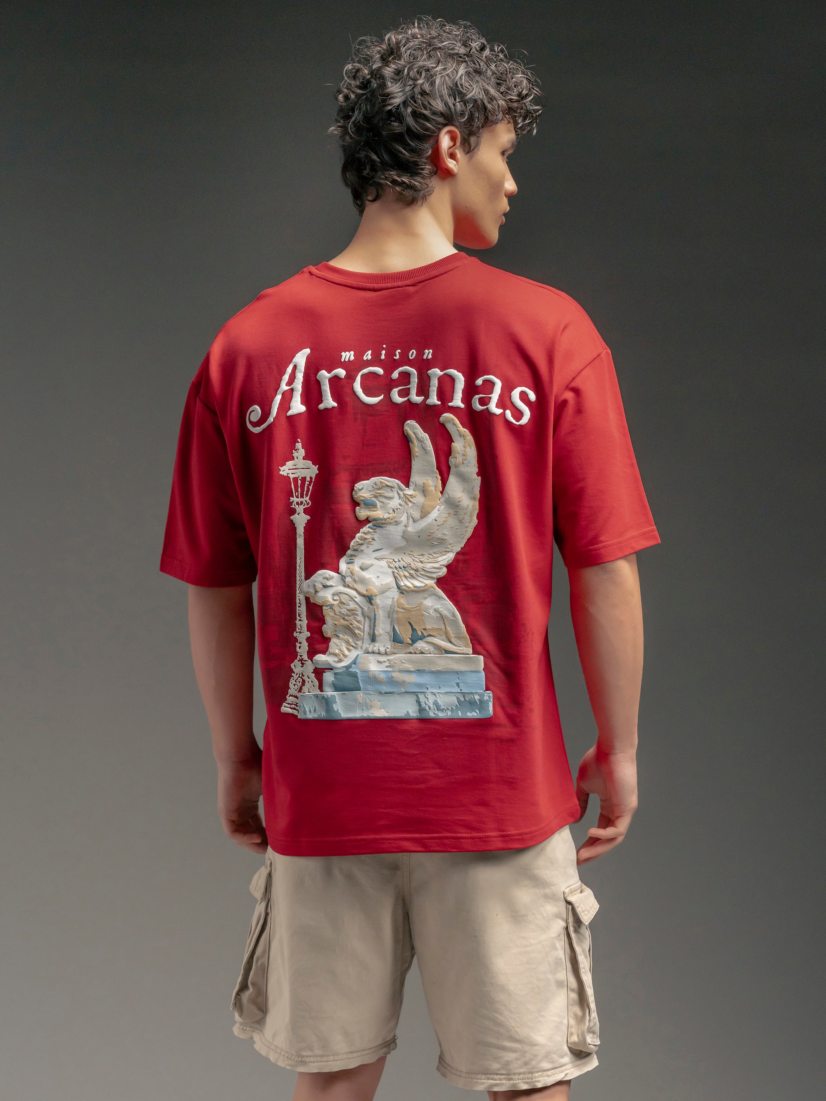 Person wearing a red t-shirt with 'maison Arcanas' design on the back
