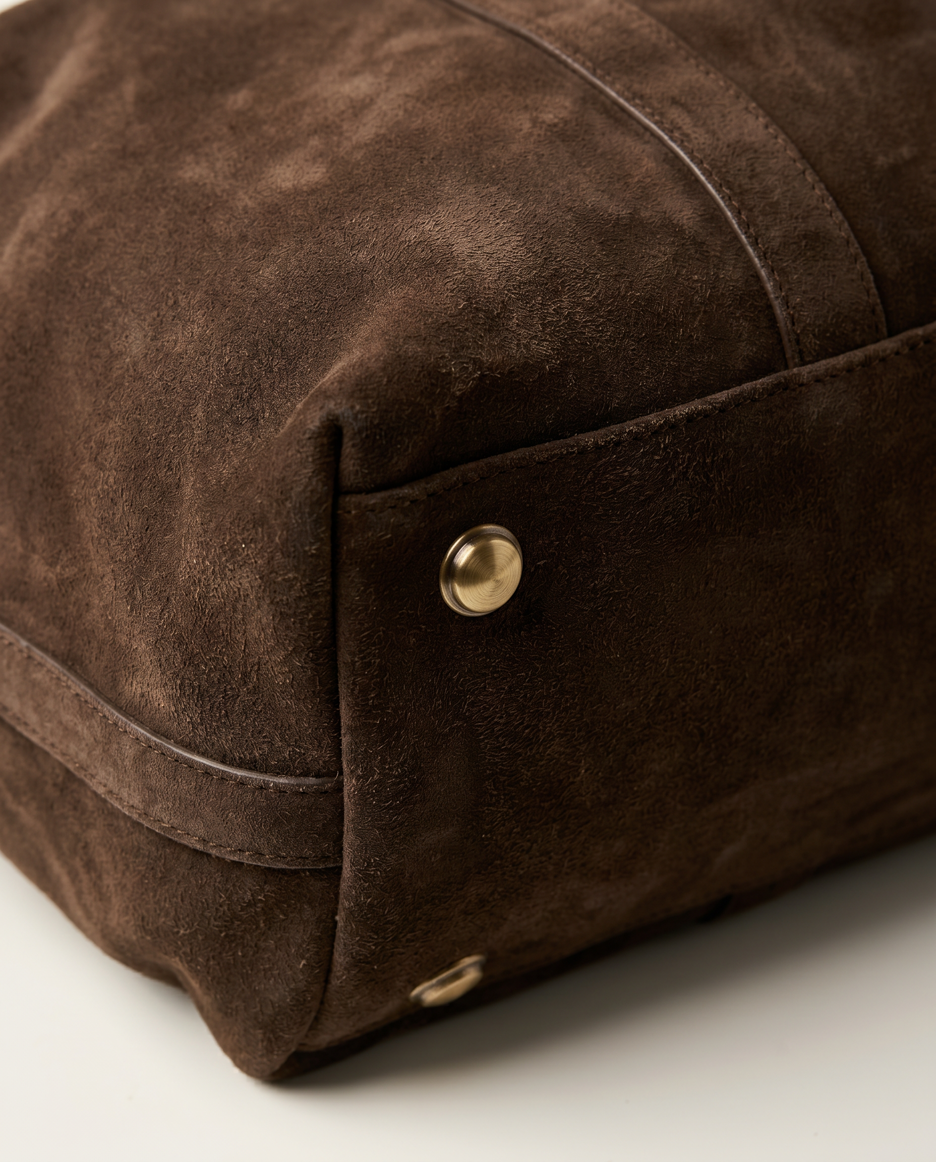 Suru Duffel suede bag corner detail with brass hardware stud