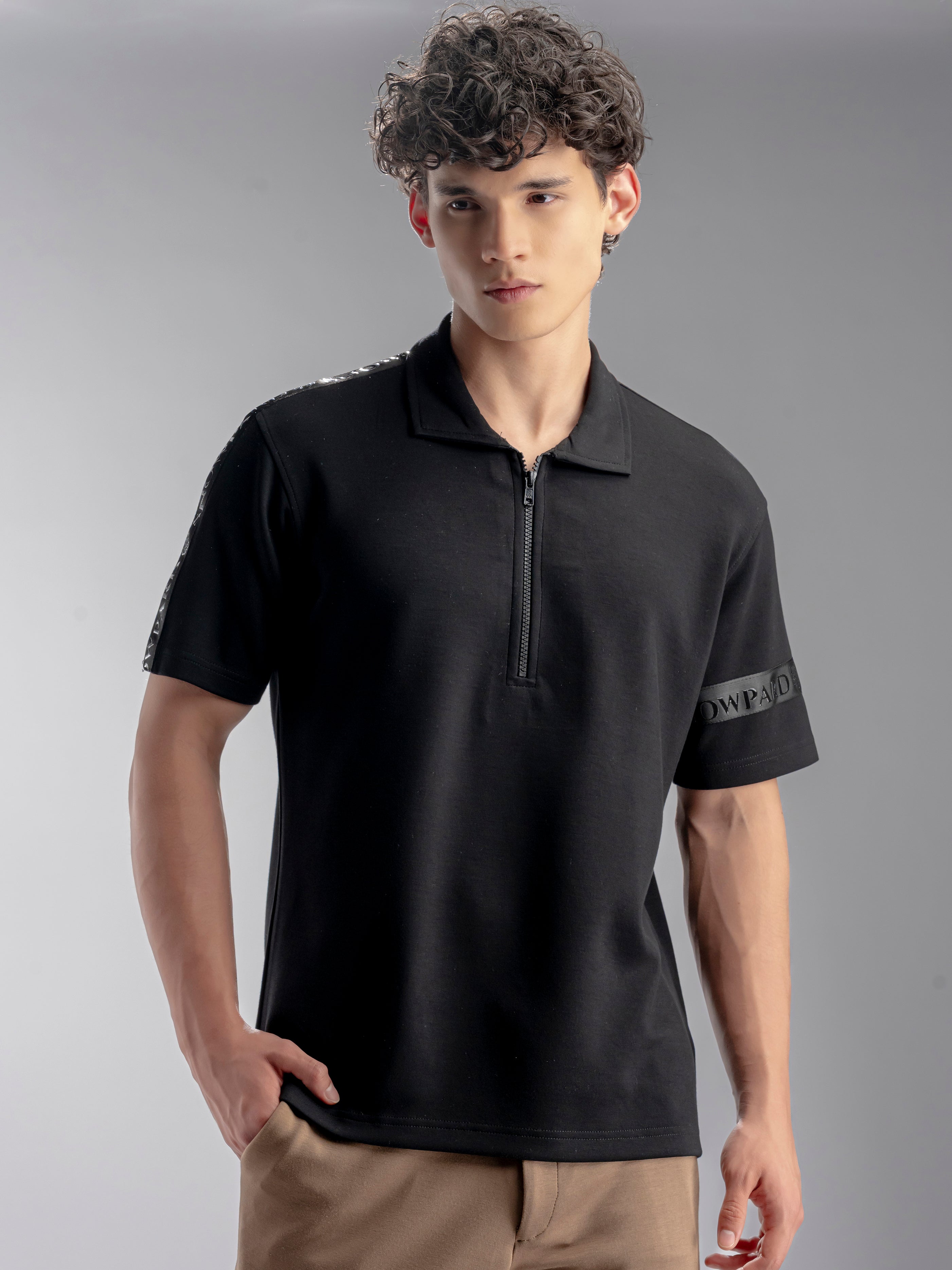 Man wearing a black polo shirt with brand logos on sleeves 