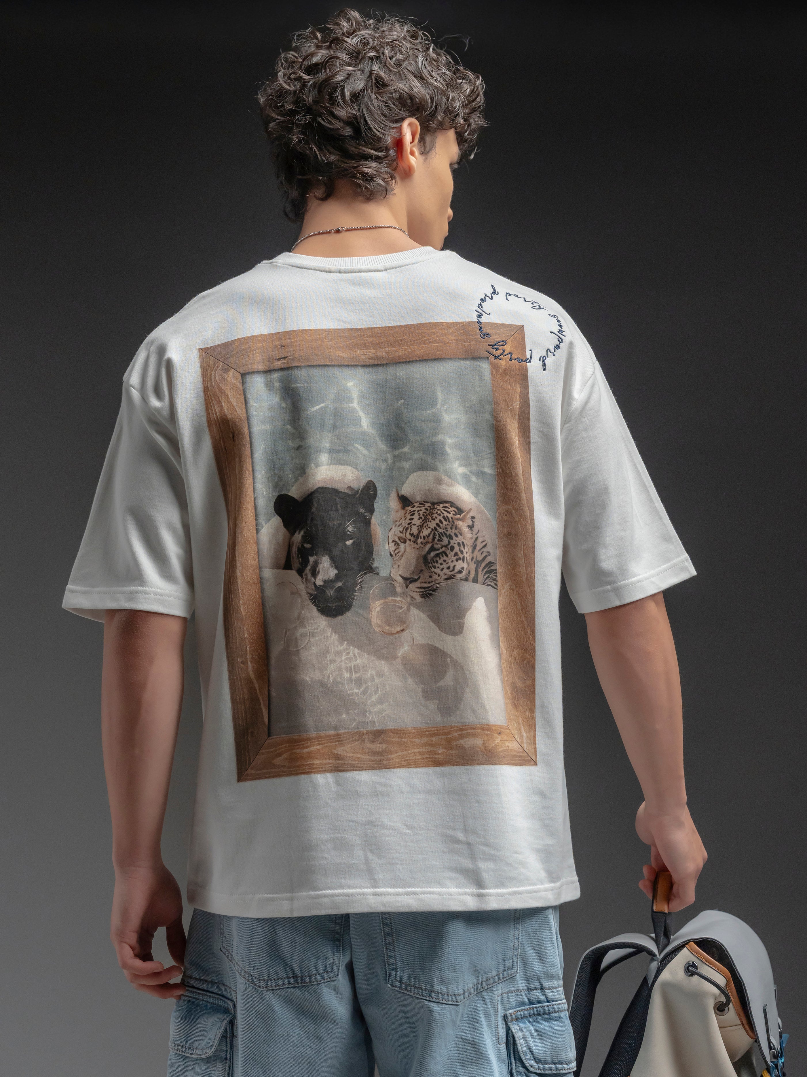 Person wearing a white t-shirt with a graphic of two animals in a frame on the back