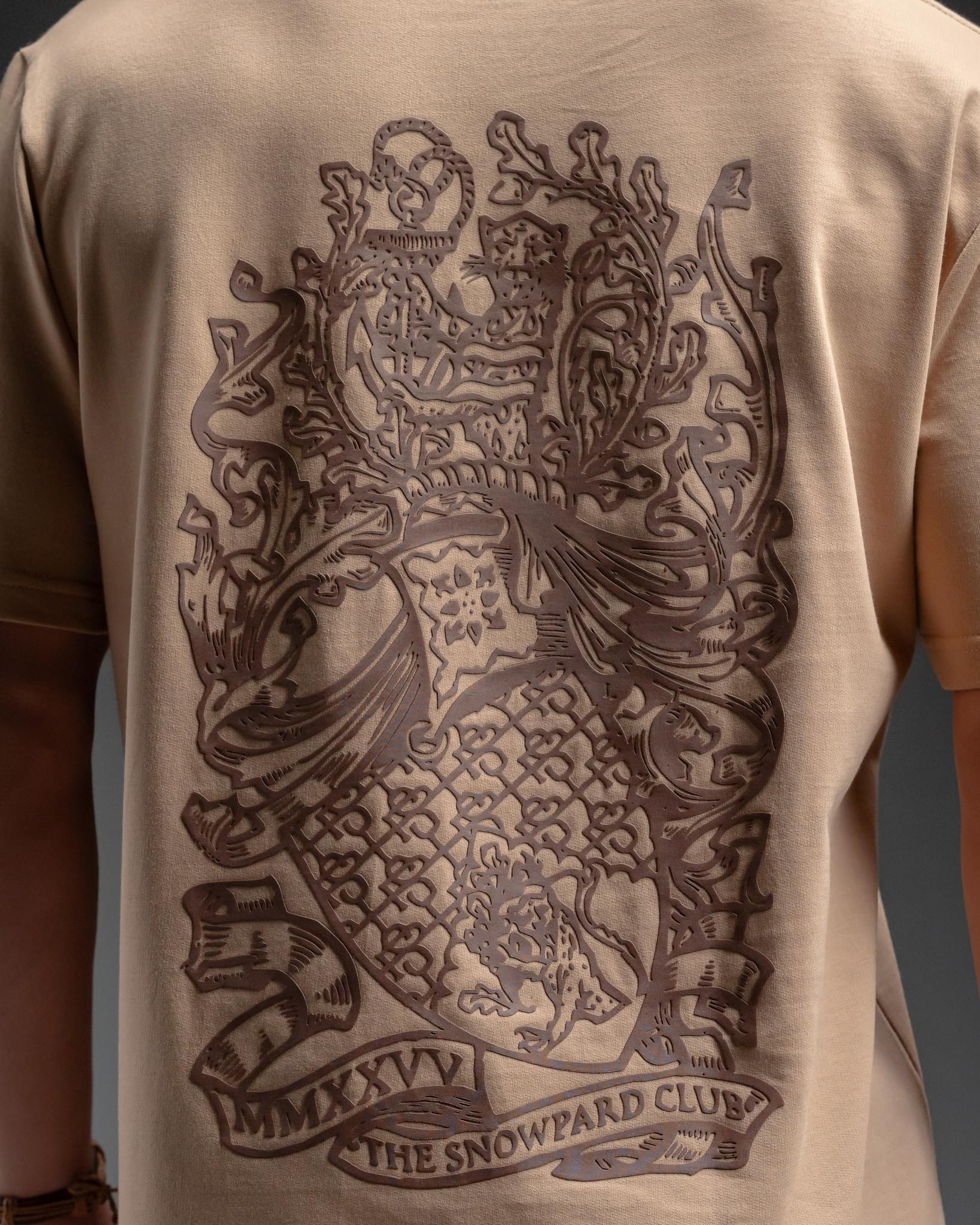 Snowpard Club Crest Relaxed Tee Desert Tan — back artwork detail, intricate crest design